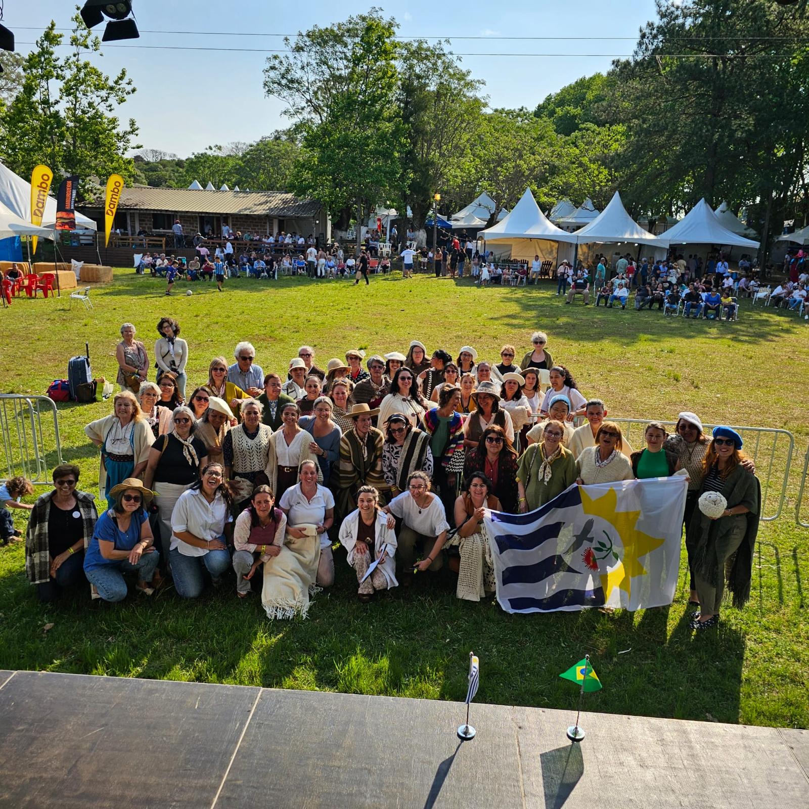 Participants of the First Binational Encounter of Women Artisans gathered on the grass holding the binational flag