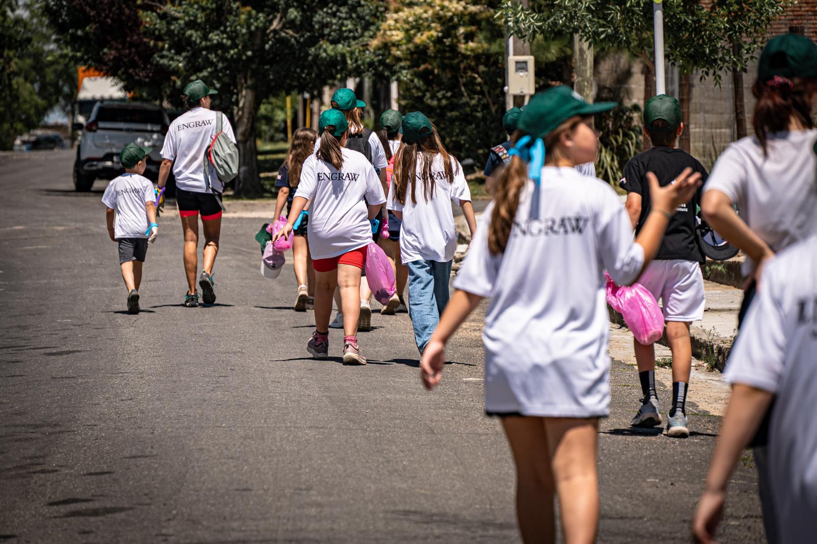 Participants of all ages walking along a street in Florida, Uruguay, collecting waste in pink bags during the plogging activity